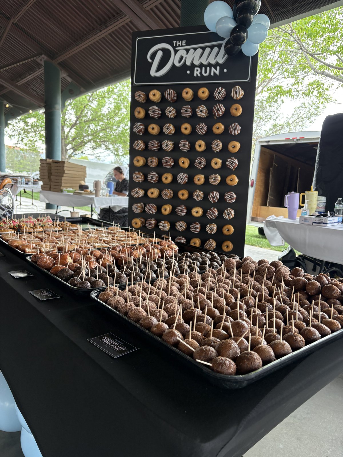 A Donut Run donut wall and trays of donut holes set up at an outdoor event